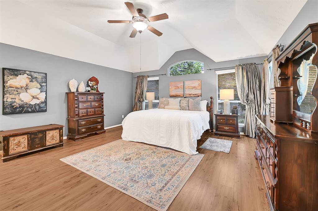 Impressive details in this oversized primary bedroom, including beautiful windows, dramatic vaulted ceilings and the lush landscaping peeking through. What a retreat!