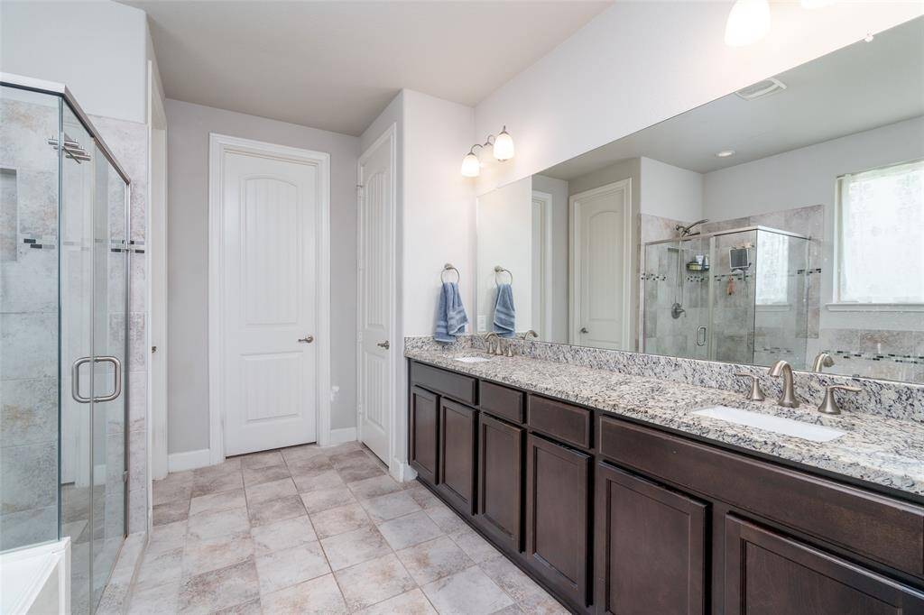 The primary bathroom boasts a spacious double sink vanity with ample counter space and generous storage, perfectly blending functionality with style.