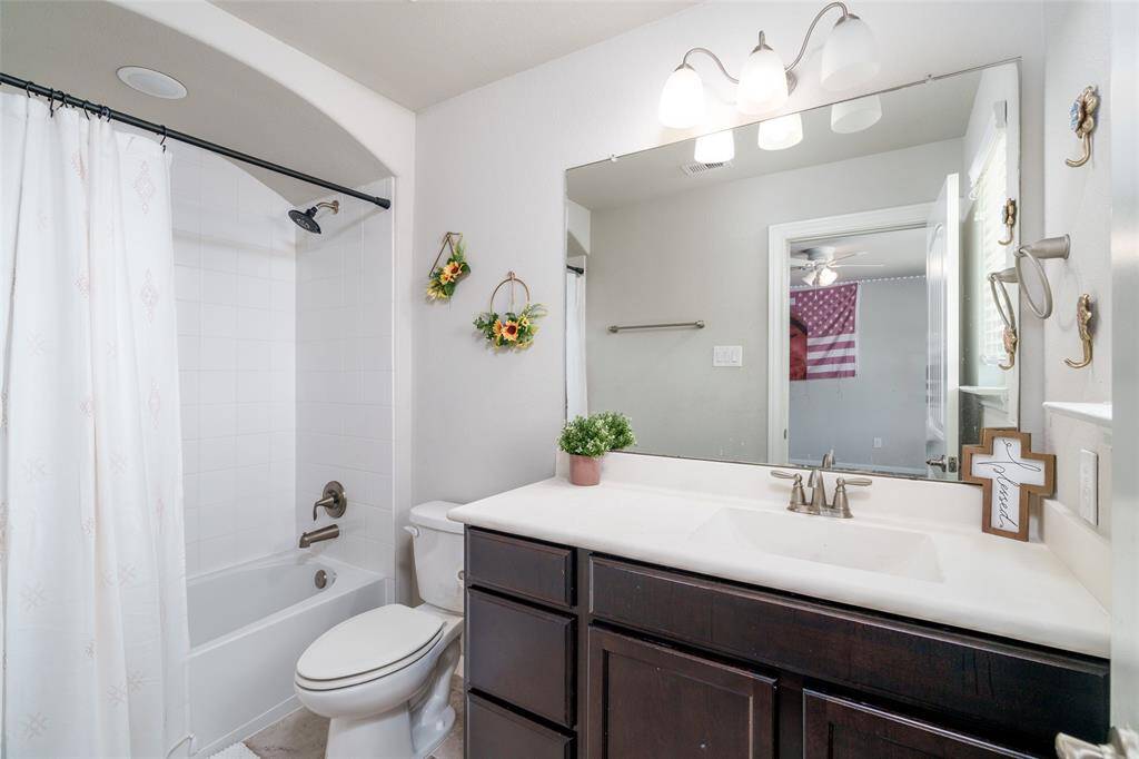 This bathroom features a stylish shower/tub combo, a dark stained vanity for ample storage, and a convenient toilet — combining function and modern design seamlessly.