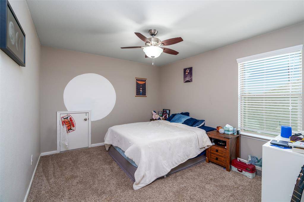This cozy bedroom features soft carpet, a ceiling fan for comfort, stylish custom paint, and a window dressed with privacy blinds for the perfect blend of light and seclusion.