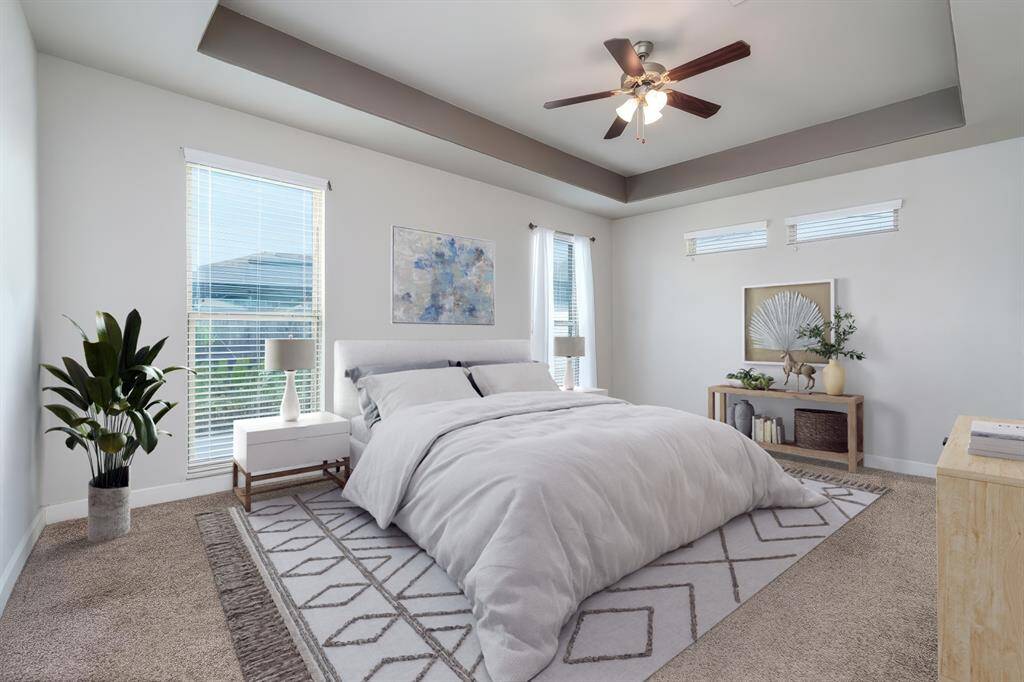 Retreat to the luxurious downstairs primary bedroom, a true sanctuary featuring plush carpet, sophisticated trey ceilings, and oversized windows with privacy blinds that fill the space with soft, natural light—perfect for relaxing at the end of the day. *Virtually Staged*