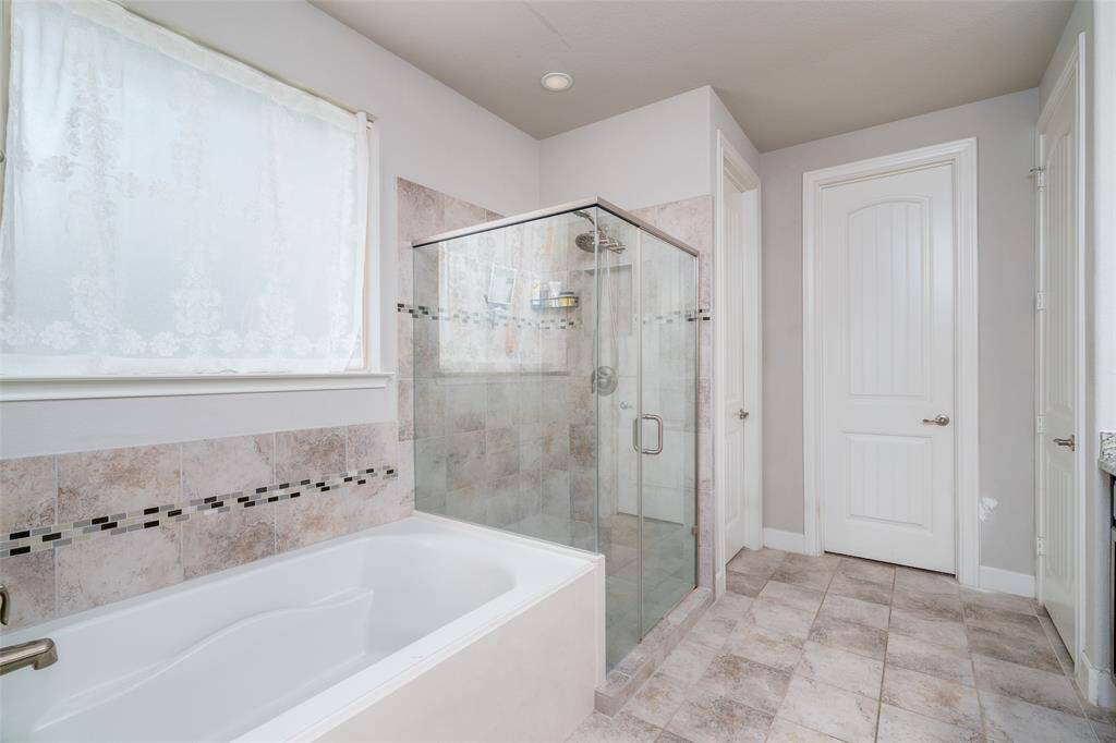 The primary bathroom offers a spa-like retreat with a luxurious soaking bathtub and an over-sized tiled walk-in shower—perfect for unwinding in comfort and style.