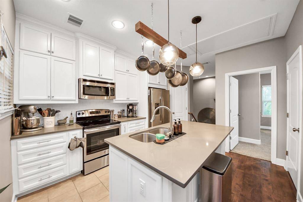 This kitchen checks every box — bright, functional, and stylish. Quartz countertops, stainless steel appliances, and tons of cabinet space make it perfect for everyday cooking or entertaining guests. The custom pot rack and pendant lighting add a designer touch, while the island offers extra prep space and seating. A layout that works, finishes that shine — all that's missing is you.