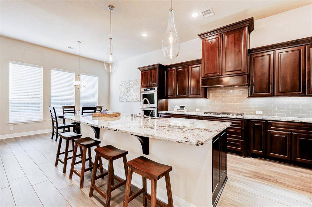 At the heart of the home, thisstunning kitchen features aspacious, thoughtfully designedlayout perfect for entertaining. Anexpansive granite island offersample workspace and casualseating, while two strikingpendant lights infuse the spacewith style and warmth.