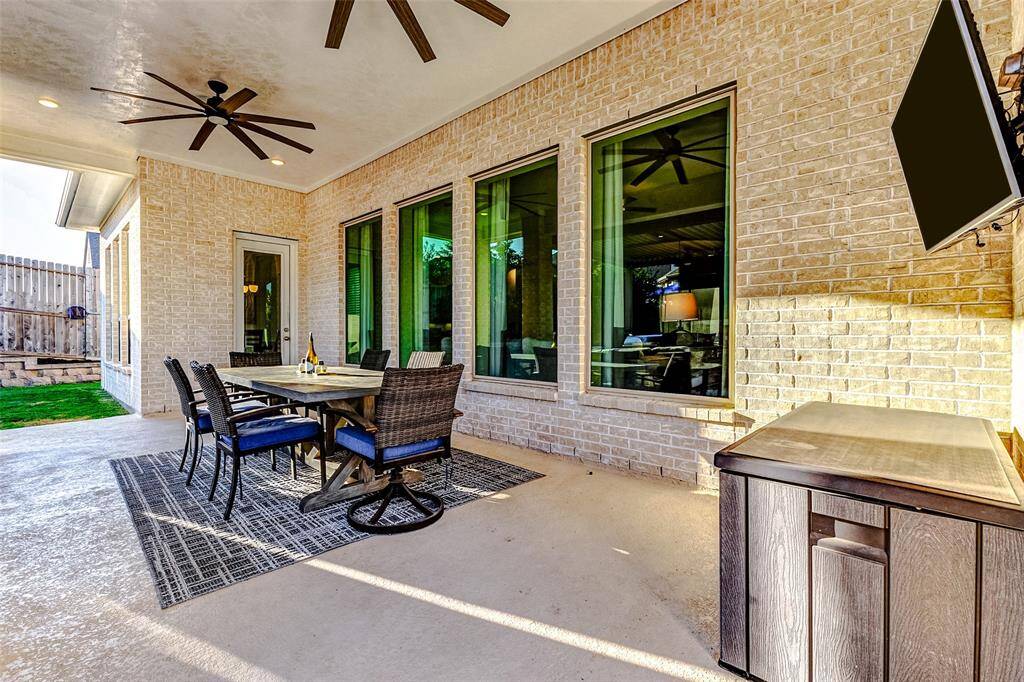 The back door opens to a spacious patio, ideal for arranging your outdoor furniture and creating a comfortable gathering space. Two ceiling fans overhead enhance air circulation, keeping the area cool and inviting even during the warmer months.