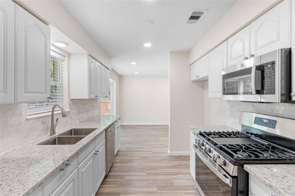 Modern kitchen with white cabinetry and granite coutnertops.