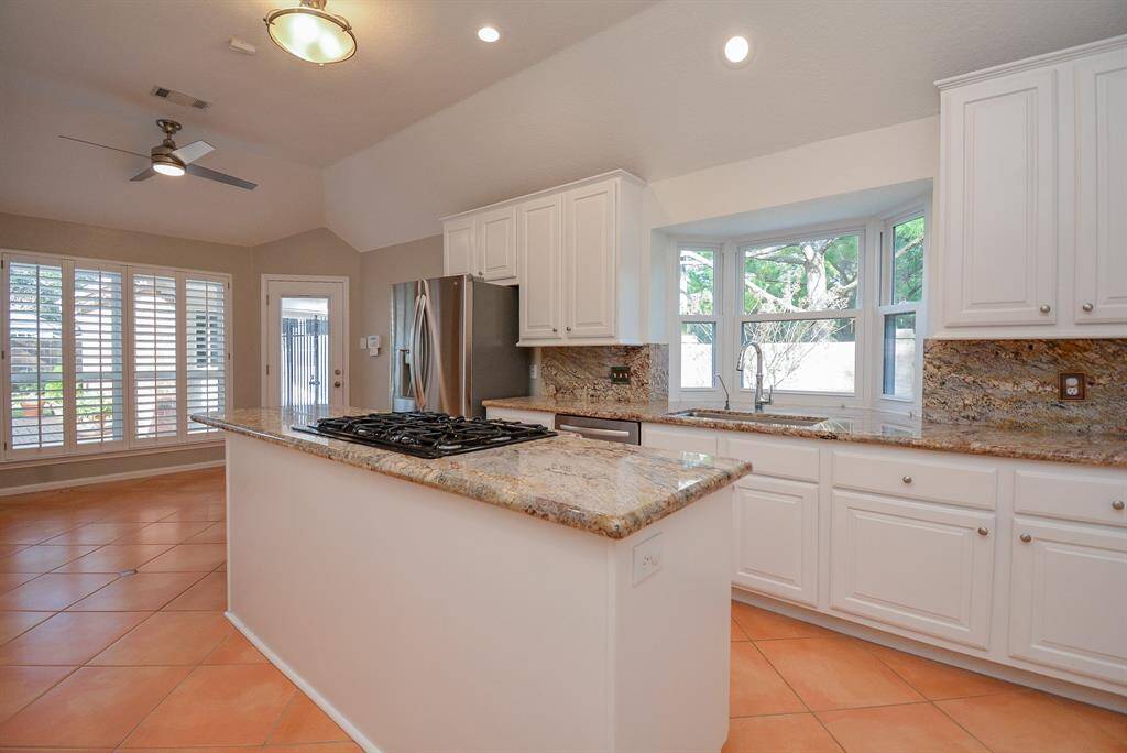 Bright kitchen with granite countertops and granite backsplash.  View to the park from the bay window above the sink