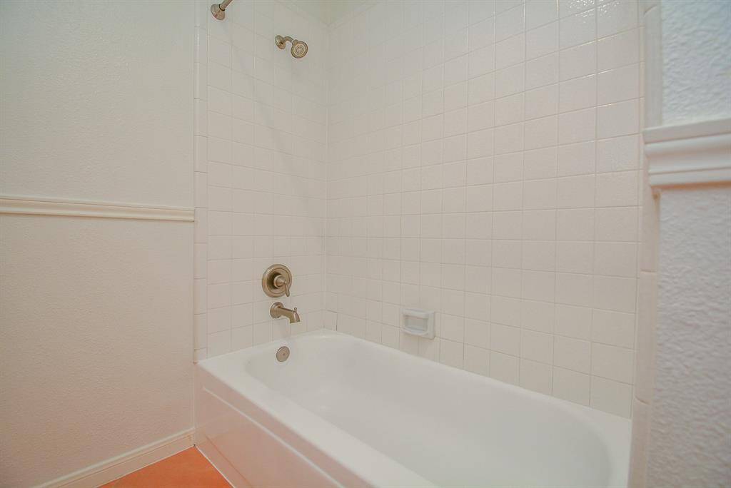 Bathtub/shower combo.  Linens cabinet across the bathtub