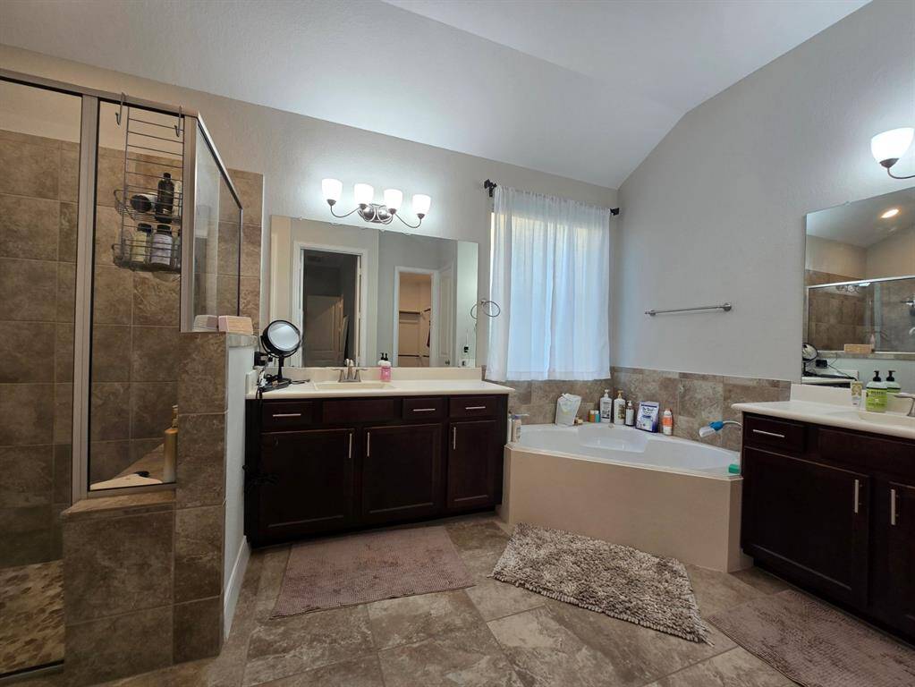 Your private spa awaits! This primary bathroom offers double vanities, a walk-in shower with bench, and a soaking tub for ultimate relaxation.