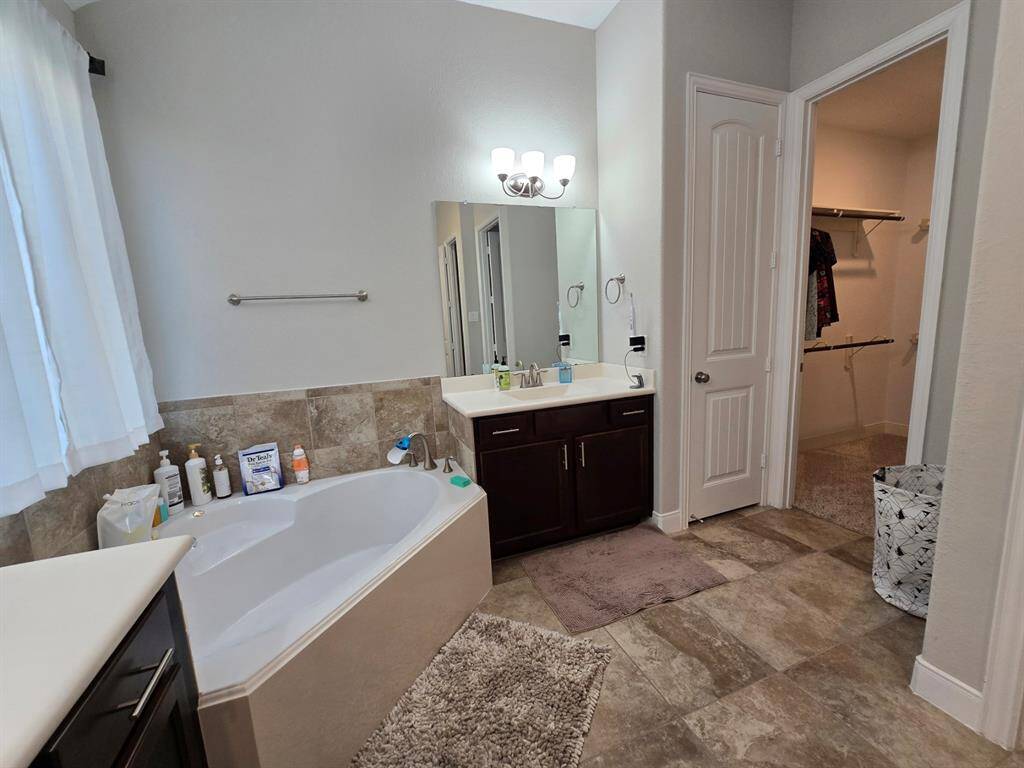 The primary bathroom retreat offers a relaxing soaking tub and entry to one of the two impressive walk-in closets.