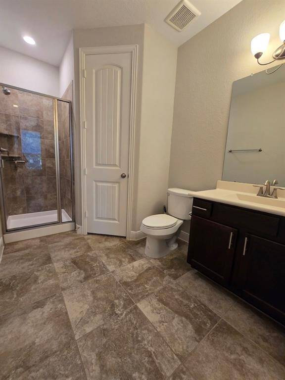 Private guest en-suite featuring a walk-in shower, elegant tile flooring, and ample storage with vanity cabinetry and a walk-in closet.