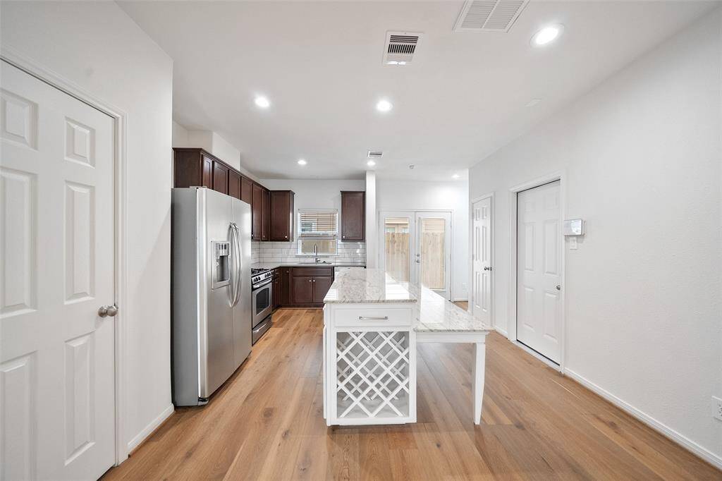 This stunning island kitchen boasts elegant granite countertops and rich walnut-stained cabinetry, offering a perfect blend of style and functionality