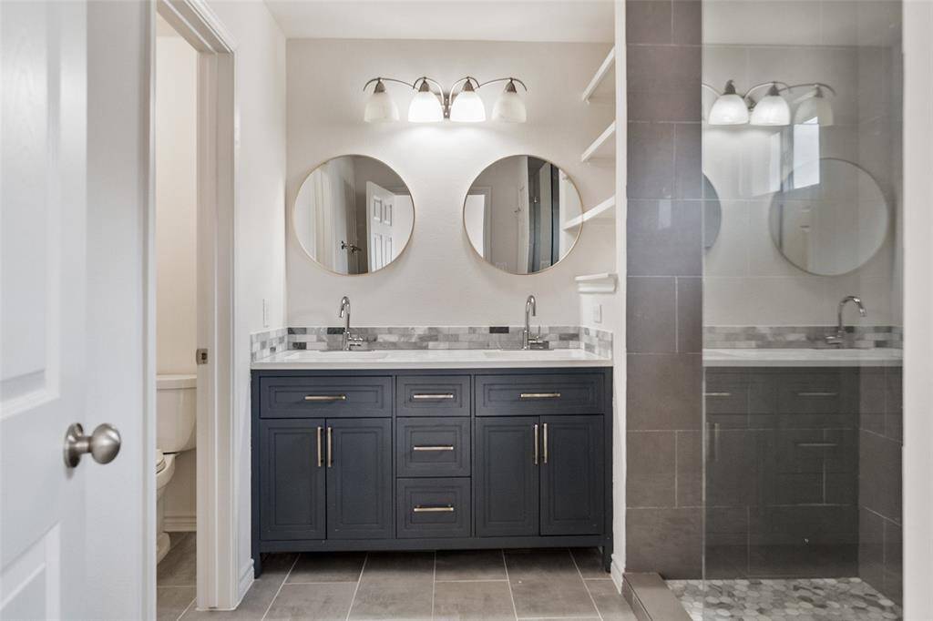 The sleek primary bath offers a stylish dual vanity, a walk-in shower, and plenty of storage space.