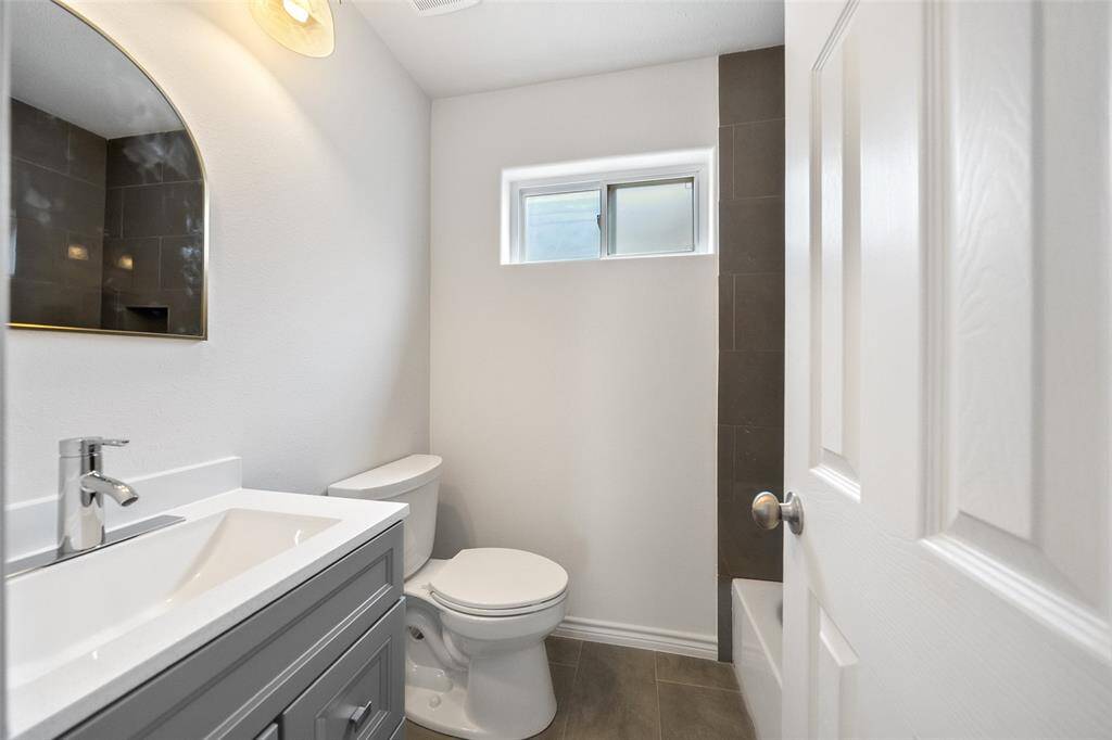 The upstairs secondary bath features a tub/shower combo and a vanity with built-in storage.
