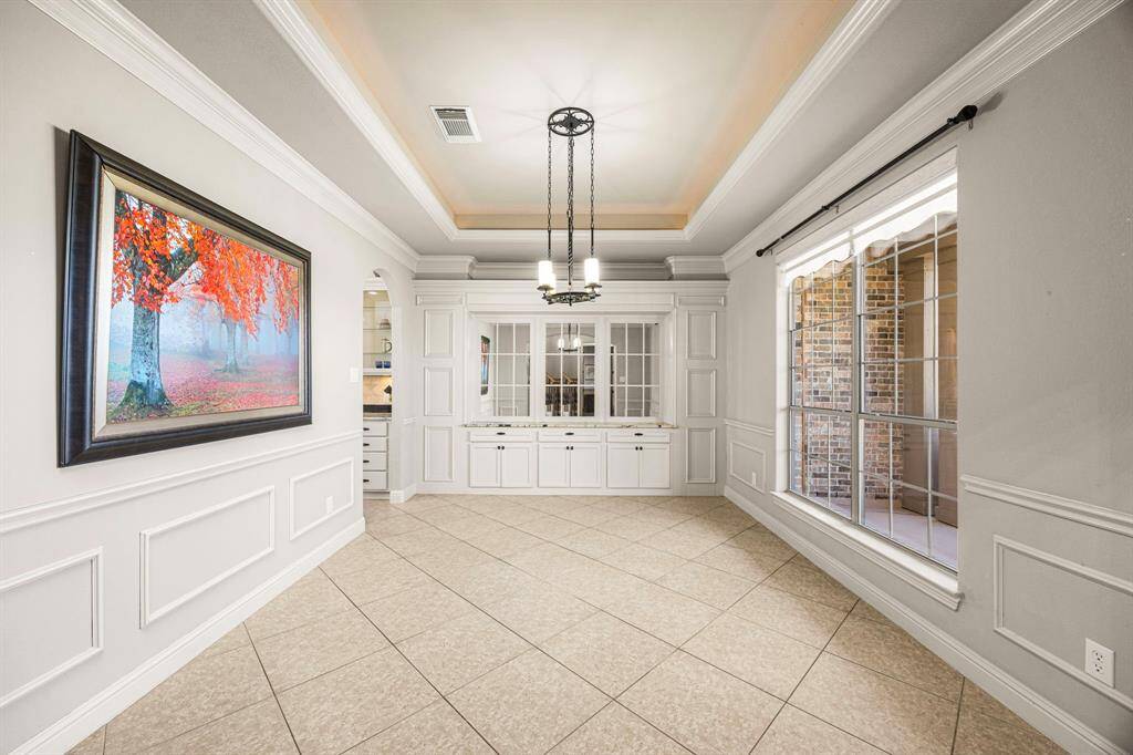The Formal Dining Room, just off the Foyer, exudes elegance with its built-in buffet area featuring a granite countertop, custom cabinetry, drawers, and mirrored-pane fronts. A large bay window bathes the space in natural light, while the 10 ft. pop-up ceiling with rope lighting and soothing paint colors enhances the inviting ambiance. For added convenience, the room offers direct access to the Kitchen, making entertaining effortless.