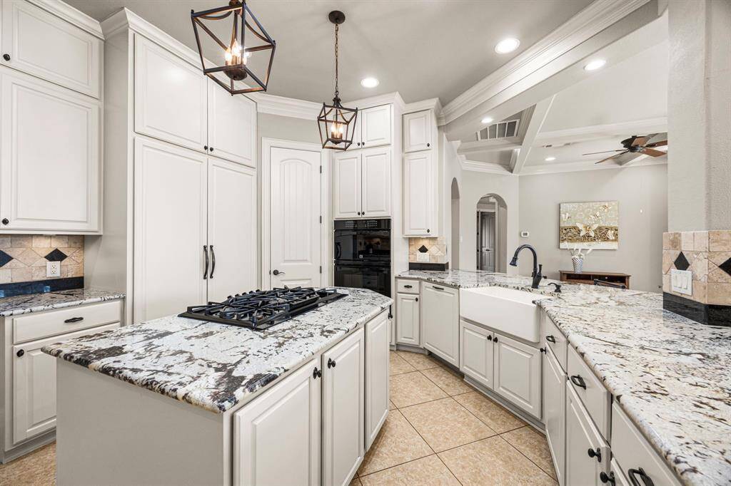 The farmhouse porcelain sink, paired with an oil-rubbed bronze faucet and matching cabinet hardware, adds a touch of rustic elegance. The spacious Breakfast Bar provides additional seating, making it a perfect spot for guests to gather and enjoy the heart of the home.