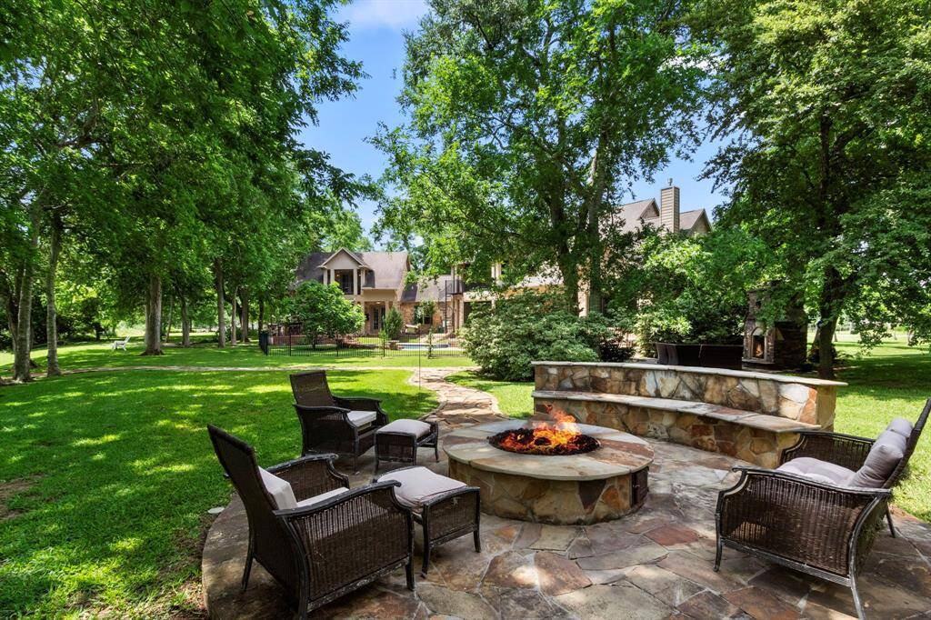 The backyard space is truly incredible. This view captures the grandeur of the expansive 1.74-acre wooded lot. Towering Pecan, Oak, and Elm trees provide a majestic canopy over multiple outdoor seating areas, all perfectly positioned to take in the stunning views of the Brazos River. One highlight of this area is the inviting gas firepit, set on elegant flagstone flooring and complemented by a matching flagstone bench—an ideal spot to relax an unwind in luxury and tranquility