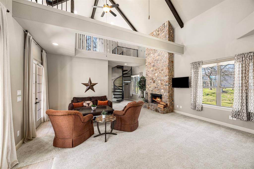 This home also features a private Guest Suite with soaring 22-foot ceilings, exposed wood beams, and a charming loft above. This area is complemented by a stunning floor-to-ceiling stone Fireplace, which can be used as either wood-burning or gas. Large windows fill the space with natural light and offer beautiful views, creating a warm and inviting retreat. A beautiful spiral staircase leads to the loft above, adding a unique architectural touch while providing a cozy elevated space that overlooks the space
