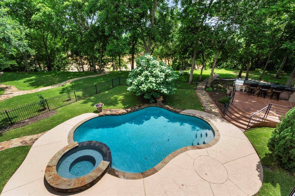 Wow! Incredible backyard space! This view from the upstairs screened-in balcony highlights the stunning pool and spa, complete with two mesmerizing fire bowls, creating a resort-like ambiance. With the Brazos River beautifully stretching across the background and majestic Pecan and Oak trees surrounding the property, this serene setting offers the perfect blend of natural beauty and relaxation.