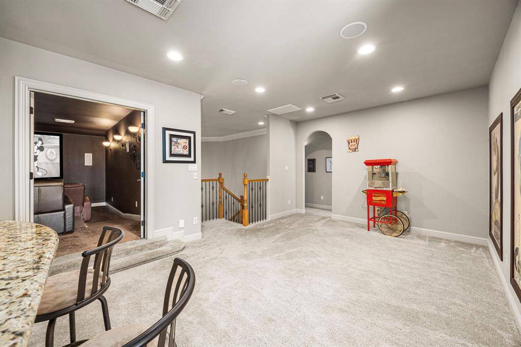 The space is large and versatile, allowing plenty of room for game tables and entertainment. It also features 2 ceiling speakers, enhancing the atmosphere for fun gatherings and relaxation. From this vantage point, you catch a glimpse of the Media Room, while the elegant archway in the distance leads to two secondary upstairs Bedrooms, each designed for comfort and privacy, making them perfect for family or guests.
