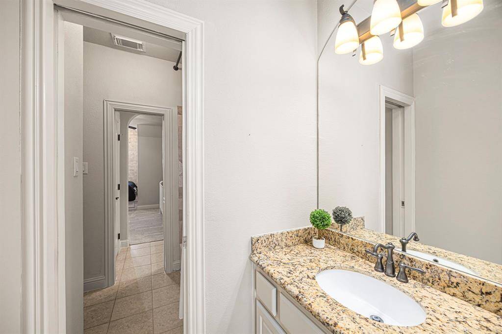 This side of the Jack and Jill bath serves the Bedroom in the previous photo and offers both style and functionality. It features a tub/shower combo, a spacious walk-in closet, and a granite countertop with an undermount oval sink. The brushed nickel faucet and three-globe light fixture add a touch of elegance to this thoughtfully designed space.