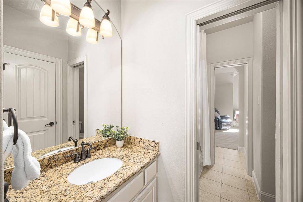 This side of the Jack and Jill bath serves the Bedroom in the previous photo.  It features a tub/shower combo, a spacious walk-in closet, and a granite countertop with an undermount oval sink. The brushed nickel faucet and three-globe light fixture add a touch of elegance to this thoughtfully designed space.