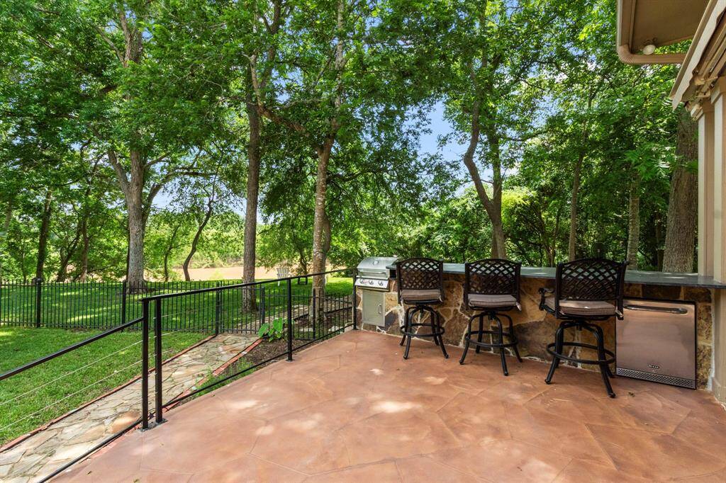 This Patio, located just off the Guest Suite, is designed for both convenience and entertainment. It features a built-in grill, built-in refrigerator, a sleek granite countertop with stone accent below, and ample space for 3-4 barstools—perfect for outdoor cooking and dining while enjoying the beautiful backyard views.