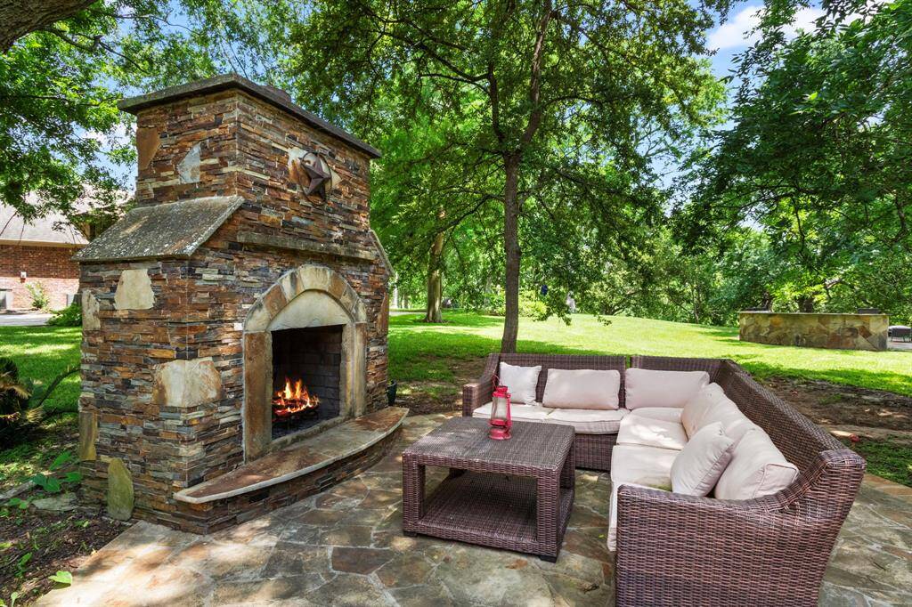 The back of the property offers several inviting seating areas to enjoy the outdoors, including this stunning stacked stone wood-burning fireplace with flagstone flooring. This cozy spot is perfect for gathering with family and friends, roasting marshmallows, or simply unwinding while taking in the serene views of the Brazos River and surrounding landscape.