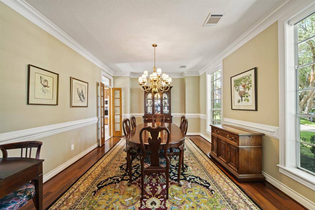Spacious Dining Room with Extensive Crown Molding, Chair Railing and Wood Flooring.