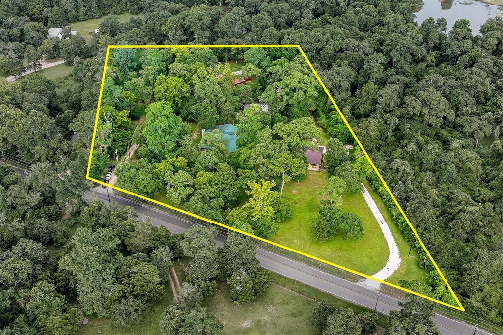 You're looking at a secluded property surrounded by lush greenery with a significant amount of tree coverage, offering privacy and a natural setting. The land is outlined, indicating a generous lot size, with a driveway leading to a house mostly hidden by trees, suggesting a peaceful, tucked-away living space.