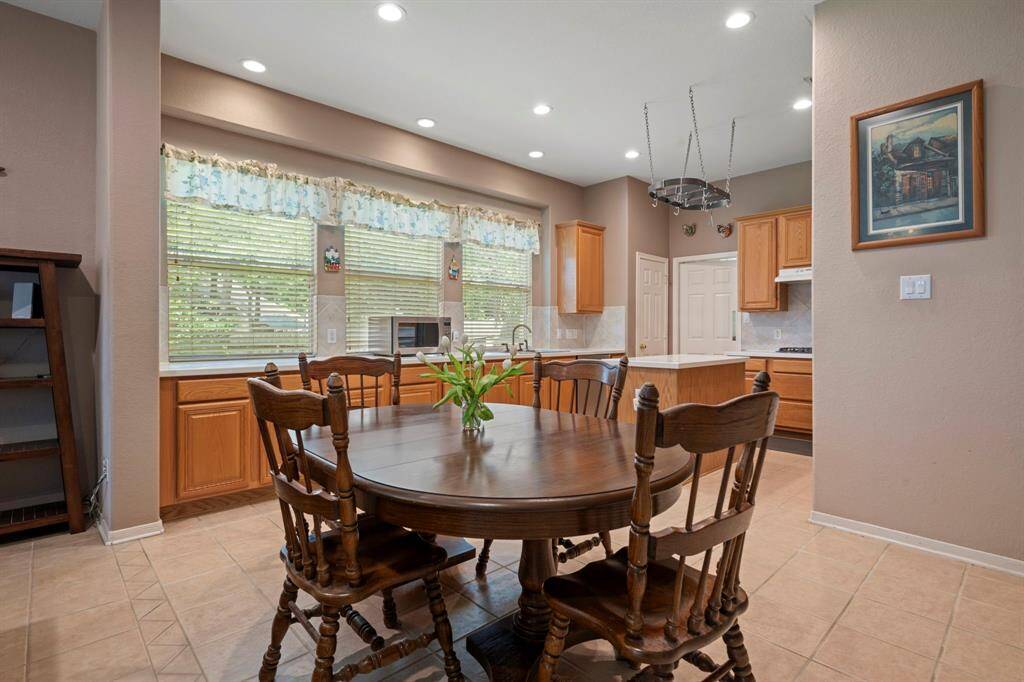 This inviting kitchen/dining or breakfast area features natural wood cabinets, corian countertops and ample natural light from large windows. The space is accented with recessed lighting and has a cozy, welcoming atmosphere.