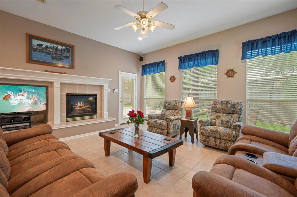 This ample sized living room features tiled floor, a fireplace, ceiling fan and lots of windows allowing for natural light to pour in creating a bright and inviting atmosphere. Also has access to the amazing backyard and patio