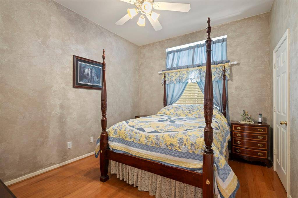 Cozy secondary bedroom featuring elegant wood flooring, a convenient ceiling fan and ample closet space.