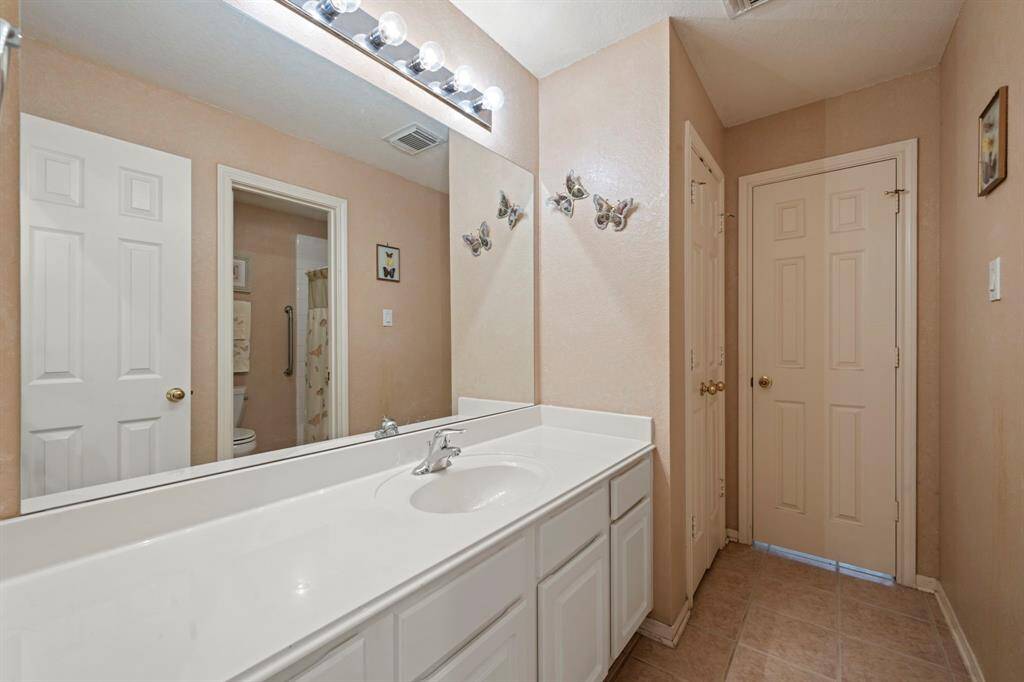 Sleek secondary bathroom with double sinks, generous counter space, ample cabinetry, and a convenient linen closet.