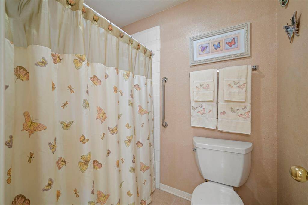 Secondary bathroom featuring a tub/shower combo, updated toilet, and soothing neutral tones.