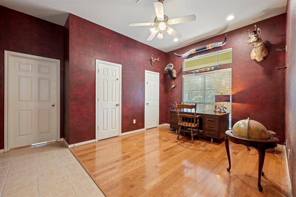 Ideal flex space for a den or study, featuring elegant wood flooring and a ceiling fan.