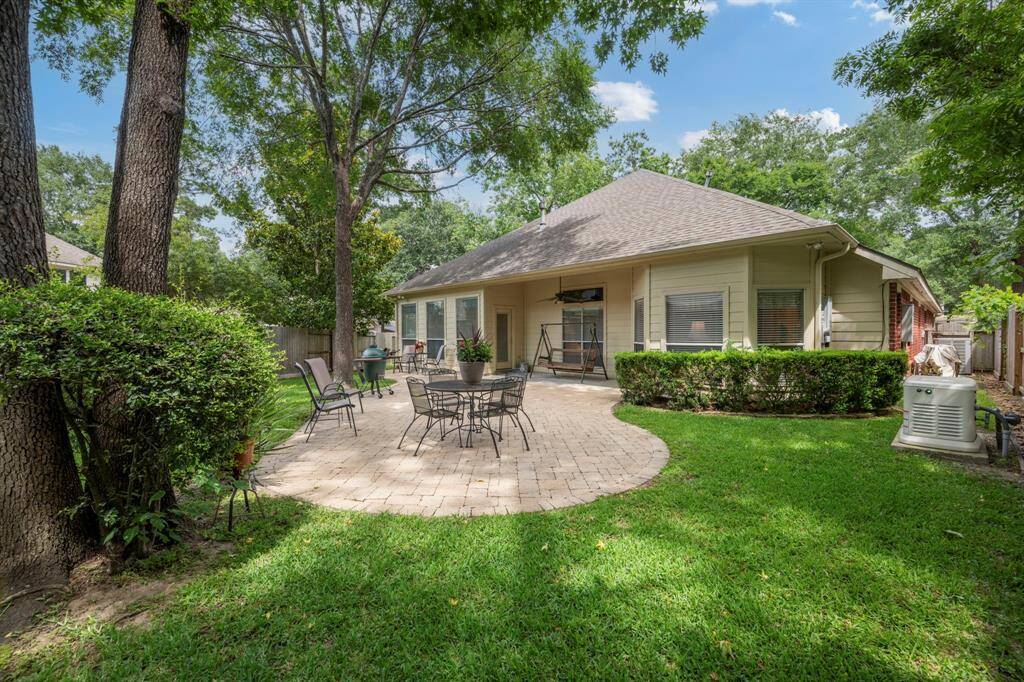Charming backyard with a spacious patio, surrounded by lush greenery and mature trees. Ideal for outdoor dining and relaxation, offering privacy and a serene atmosphere.