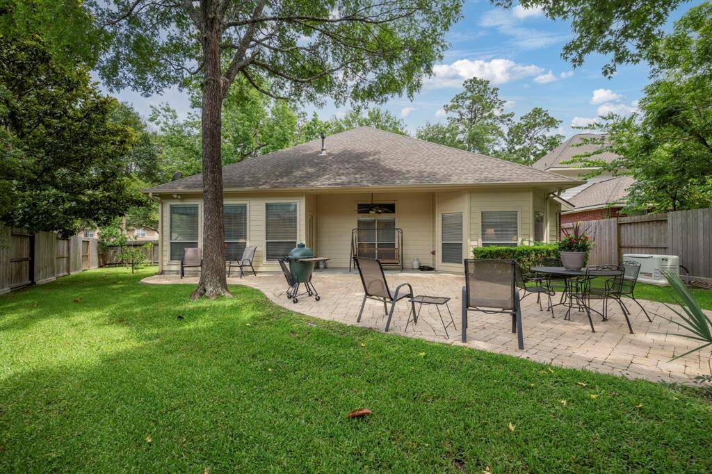 This photo showcases a spacious backyard with a well-maintained lawn and a large patio area. Lots of space for patio furniture and grill , making it ideal for entertaining. Mature trees provide shade, and the space is enclosed by a wooden fence, offering privacy.