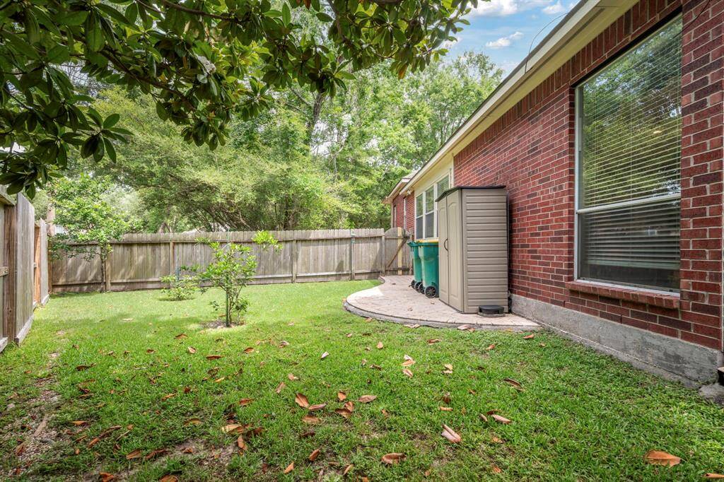 The patio extends around the corner where you'll find a small paved area with space for storage and trash bins. Surrounded by lush lawn & trees and even some small fruit trees.
