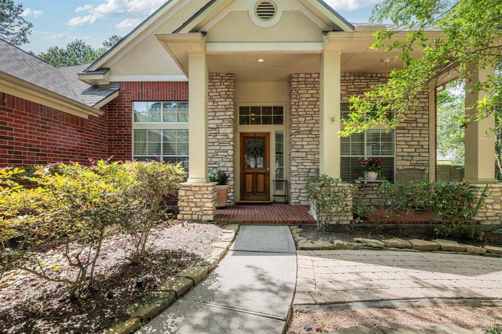 Home has a welcoming front entrance featuring a combination of brick and stone accents. The landscaped path leads to a cozy porch, perfect for relaxing outdoors.