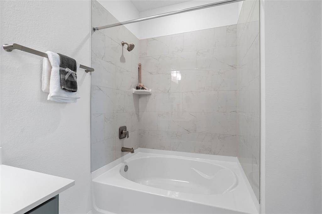 This primary bathroom also features this oversized tub and shower combination with tile surround.