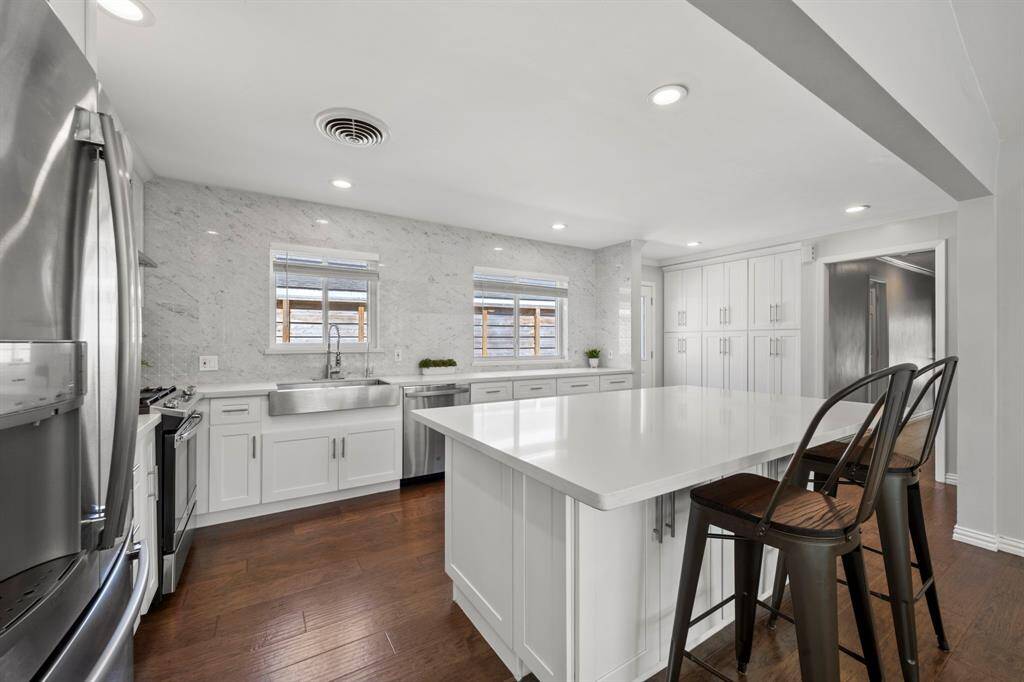 The island kitchen is a chef’s dream, offering abundant storage, generous counter space, an eat-in bar, and a beautifully designed pantry. Highlights include a stainless farmhouse sink and the marble backsplash that extends to the ceiling for a striking finish.
