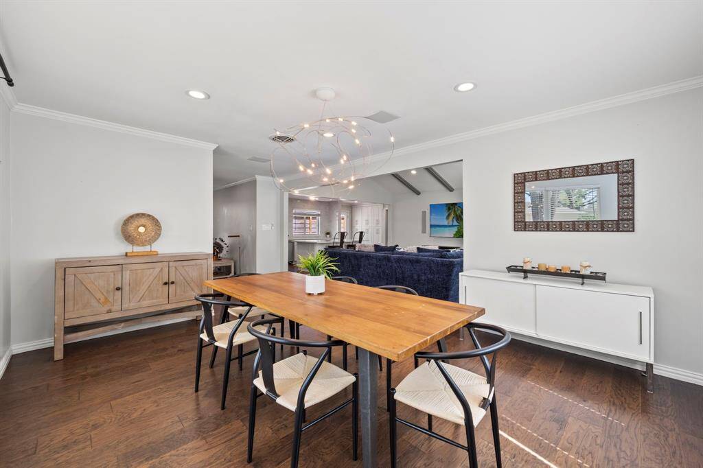 View of the formal dining area, with a whimsical and eclectic chandelier, crown molding and open to the family room.