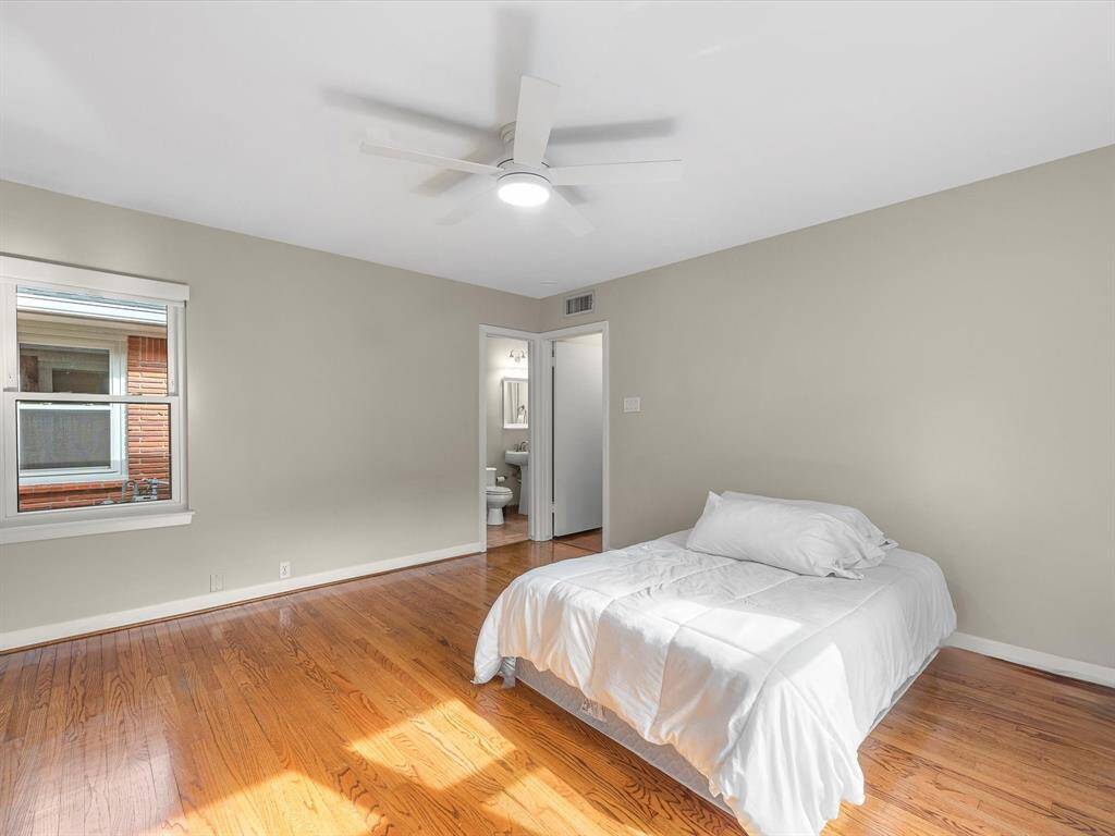 Spacious primary bedroom with abundant natural light and hardwood floors.
