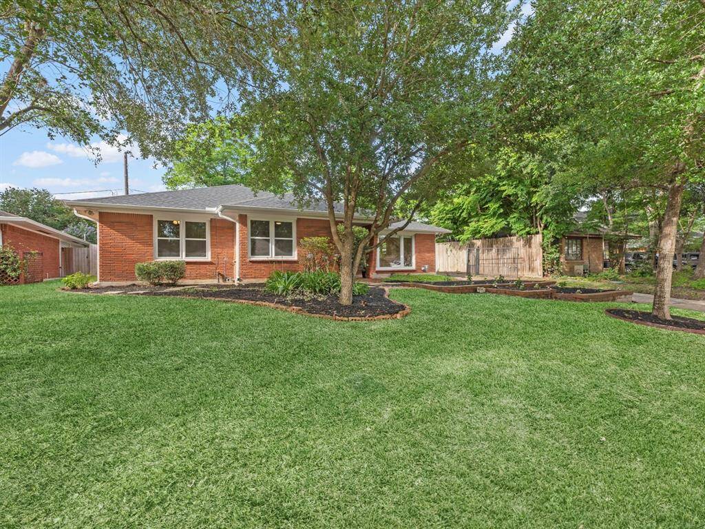 Charming front yard with lush greenery and mature trees.