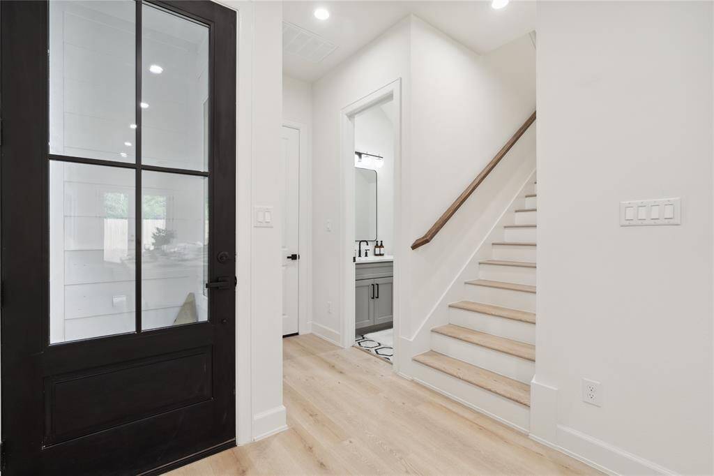 Enter a functional foyer featuring a guest bath and discreet stairs to a secondary living area. The open layout seamlessly connects to the first-floor living area, creating a welcoming space for daily living and entertaining.