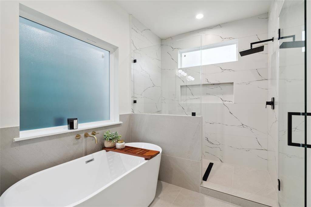 Enjoy a beautifully designed frameless walk-in shower with sleek, modern fixtures and a standalone tub for ultimate relaxation. This spacious retreat blends elegance and comfort, offering a luxurious bathing experience.