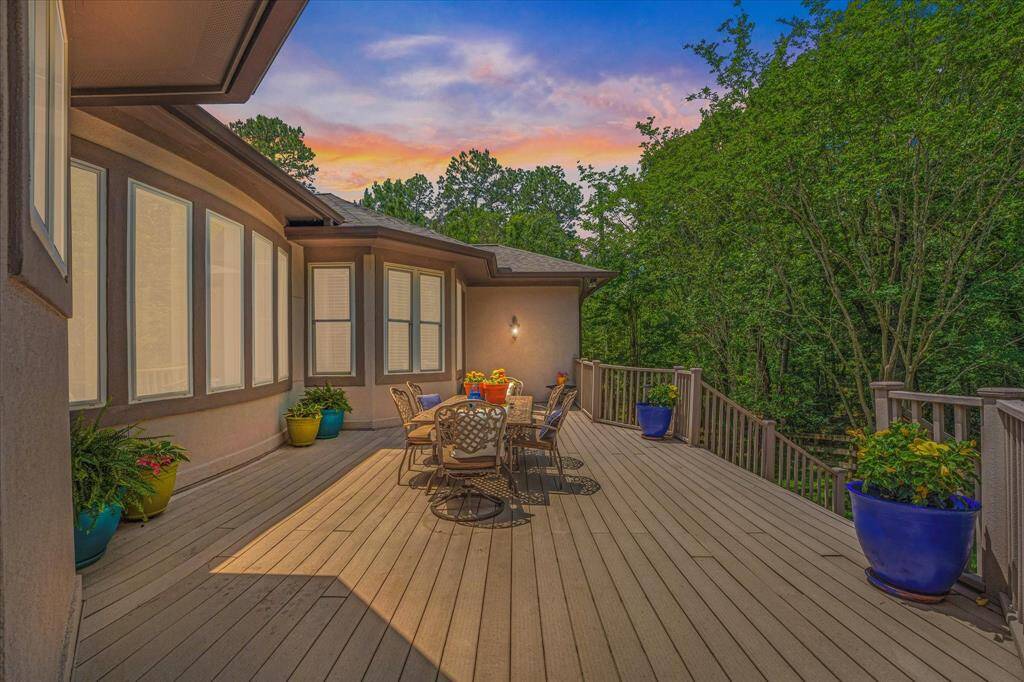 This photo showcases a spacious deck with outdoor seating with complete privacy due to woods! . It offers a serene, wooded view, perfect for relaxation and entertaining, set against a beautiful sunset sky.