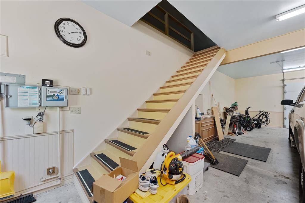 Stairs lead to extra storage area.  Work bench/cabinetry with sink is behind the stairs!