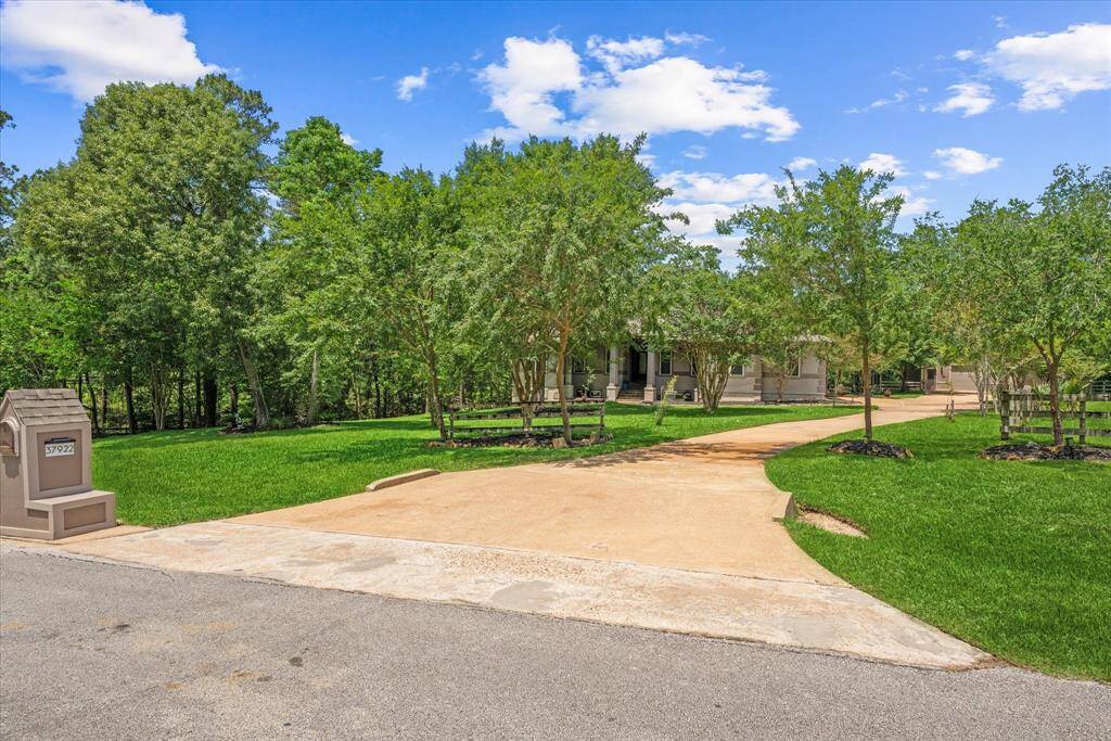 Charming home with a 130 ft driveway, surrounded by lush greenery and mature trees. The front yard is spacious and well-maintained, offering a welcoming entrance.